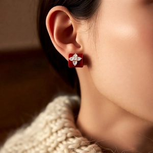 Gros plan d'une boucle d'oreille fleur rouge avec cristaux portée pour un style élégant
