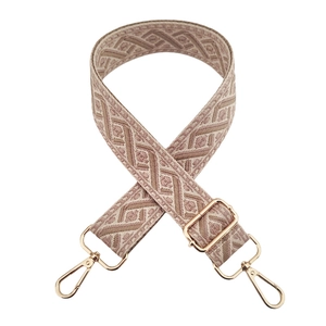 Detail of woven bag strap with beige and brown geometric patterns and gold metal buckles