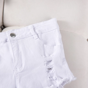Detailed view of white distressed denim shorts featuring metal button and frayed edges