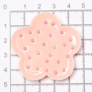 Pink star-shaped miniature dollhouse plate with polka dots shown on a scale mat