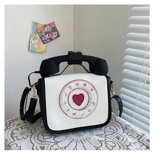 Detail shot of a creative telephone shaped PU crossbody bag with a pink heart dial.