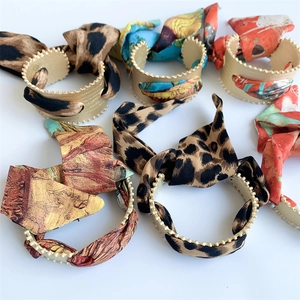 Close-up of matte gold wavy bangles with leopard print and floral silk fabric details