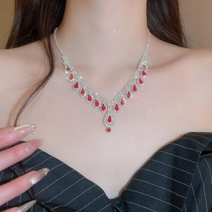 Close-up of sparkling necklace with red teardrop crystal and clear diamonds on model