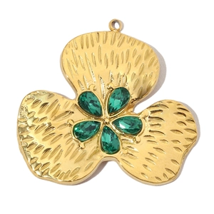 Macro detail of gold flower pendant featuring five green teardrop gemstones on petals