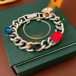 Detail of silver Cuban chain bracelet featuring five colored gemstones and safety clasp