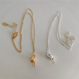 Detail of silver and gold knot pendant necklaces with adjustable fine cable chains