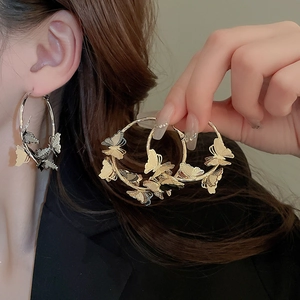 Detailed macro view of gold and silver butterfly hoop earrings with realistic 3D textures