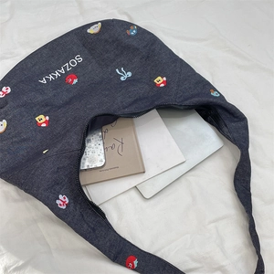 Detail of a denim hobo bag with colorful embroidery showing large interior capacity
