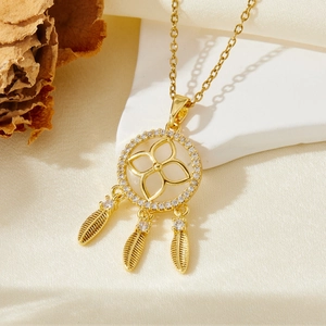 Détail d'un collier pendentif attrape-rêves doré avec plumes et zircons scintillants