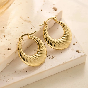 Détail macro des boucles d'oreilles croissant plaquées or 18 carats avec texture spirale