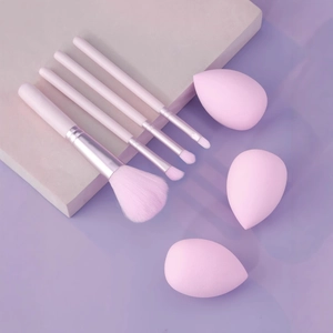 Pink makeup tool set including four brushes and three sponges on geometric background