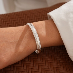 Detailed view of silver snake chain bracelet with textured horizontal patterns on wrist