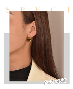 Close-up of model wearing a round gold-plated tiger eye stone stud earring in retro style