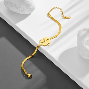 Elegant gold clover charm stainless steel snake chain bracelet on a white geometric stand