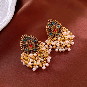 Detail shot of vintage golden tassel earrings with enamel patterns and white pearls