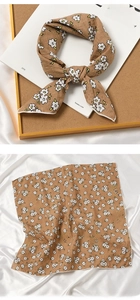 Detail view of brown cotton linen scarf with white floral print tied on a book