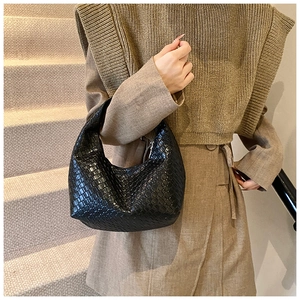 Detailed view of black woven leather texture on a stylish croissant hobo bag