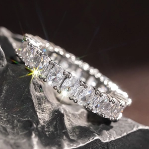 Macro shot of oval-cut eternity ring with sparkling stones on textured black rock