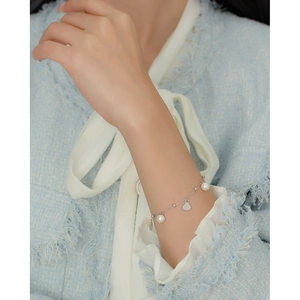 Elegantes s925 Silberarmband mit weißen Perlen und Muschelanhänger am Handgelenk