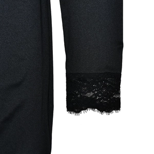 Dettaglio della manica di un abito nero elegante con pizzo delicato e tessuto liscio