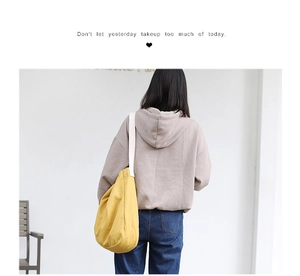 Detail of yellow canvas tote bag with white wide strap and inspirational quote embroidery