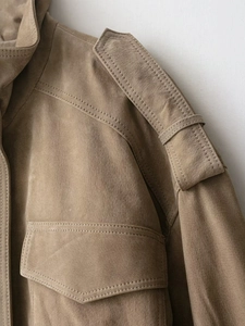 Close-up of tan suede jacket featuring detailed shoulder straps and clean stitching
