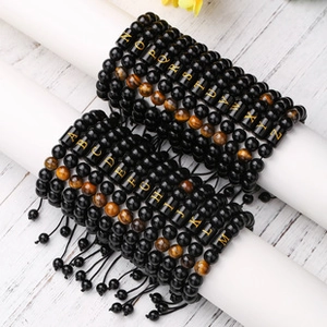 Close-up of adjustable tiger eye and black bead bracelets with gold letter charms