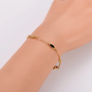 Elegant gold chain bracelet featuring black geometric spindle charms on a female model wrist