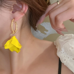 Close-up of yellow petal flower earrings with gold hoop on model for summer vacation style