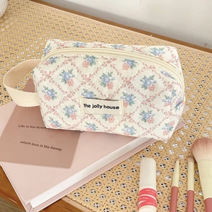 Detail of floral quilted cosmetic bag with top zipper and portable side handle