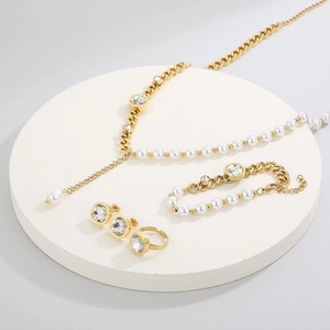 Detailed set of gold tone jewelry with pearls and square zircons on display stand