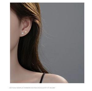 Close-up of star-shaped stud earrings with zircon inlay worn by a model