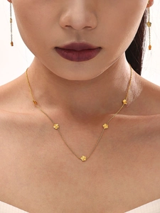 Close-up of gold-plated titanium flower pendant necklace and matching drop earrings on a model