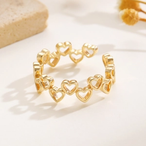 Dettaglio dell'anello aperto dorato con un delicato motivo a forma di cuore traforato