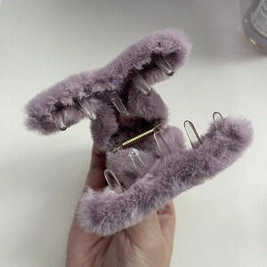 Dettaglio della molletta per capelli in peluche viola con denti trasparenti e molla dorata