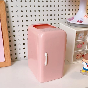 Macro view of pink mini fridge-shaped pen holder with cute stickers on desk