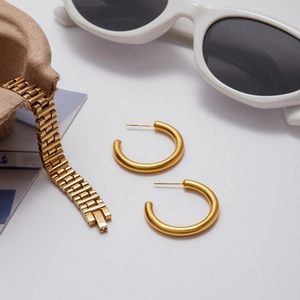 Detailed view of chunky 18K gold plated hollow C-hoop earrings and metal link bracelet