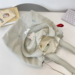 Macro view of canvas tote bag with rabbit embroidery showing spacious inner pocket