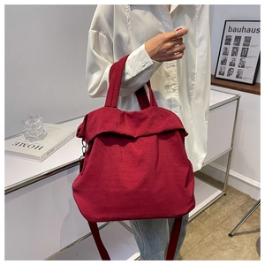 Detail of dark red lightweight nylon tote bag worn by model in minimalist setting