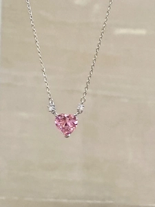 Close-up of a pink heart-shaped crystal pendant on a delicate silver necklace chain