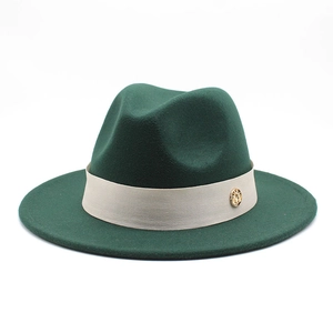 Close-up of dark green wool fedora with cream band and gold metal logo detail