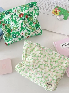 Floral print cotton makeup bags in green colors shown on a desk with accessories