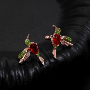 Macro shot of colorful hummingbird earrings with red stones and green crystals