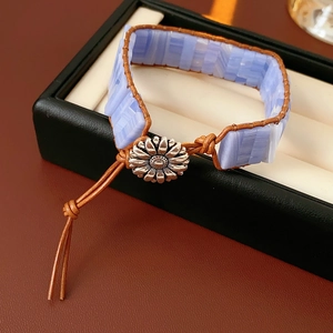 Dettaglio del bracciale etnico in pelle con pietra blu e bottone metallico a girasole