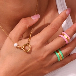 Close-up of gold water ripple ring with pink and green enamel worn by a female model