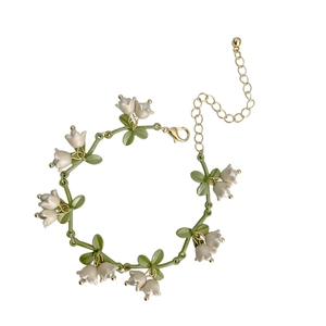 Elegant lily of the valley bracelet with green leaves and white buds on white background