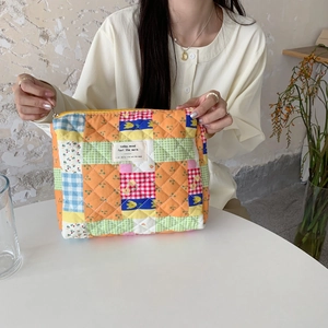 Detailed close-up of quilted floral patchwork makeup bag with yellow zipper and label