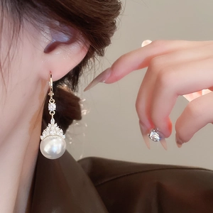 Gros plan d'une boucle d'oreille en perle plaquée or avec zircone portée pour un look élégant