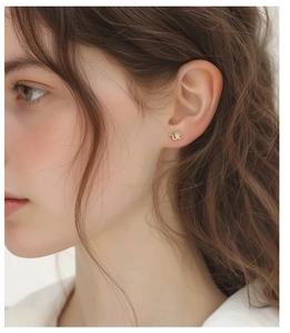 Close-up of elegant gold snake-shaped stud earring with detailed scale texture on ear
