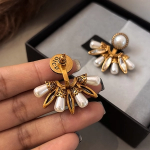 Détail macro de boucles d'oreilles perles en éventail avec monture dorée et gravure